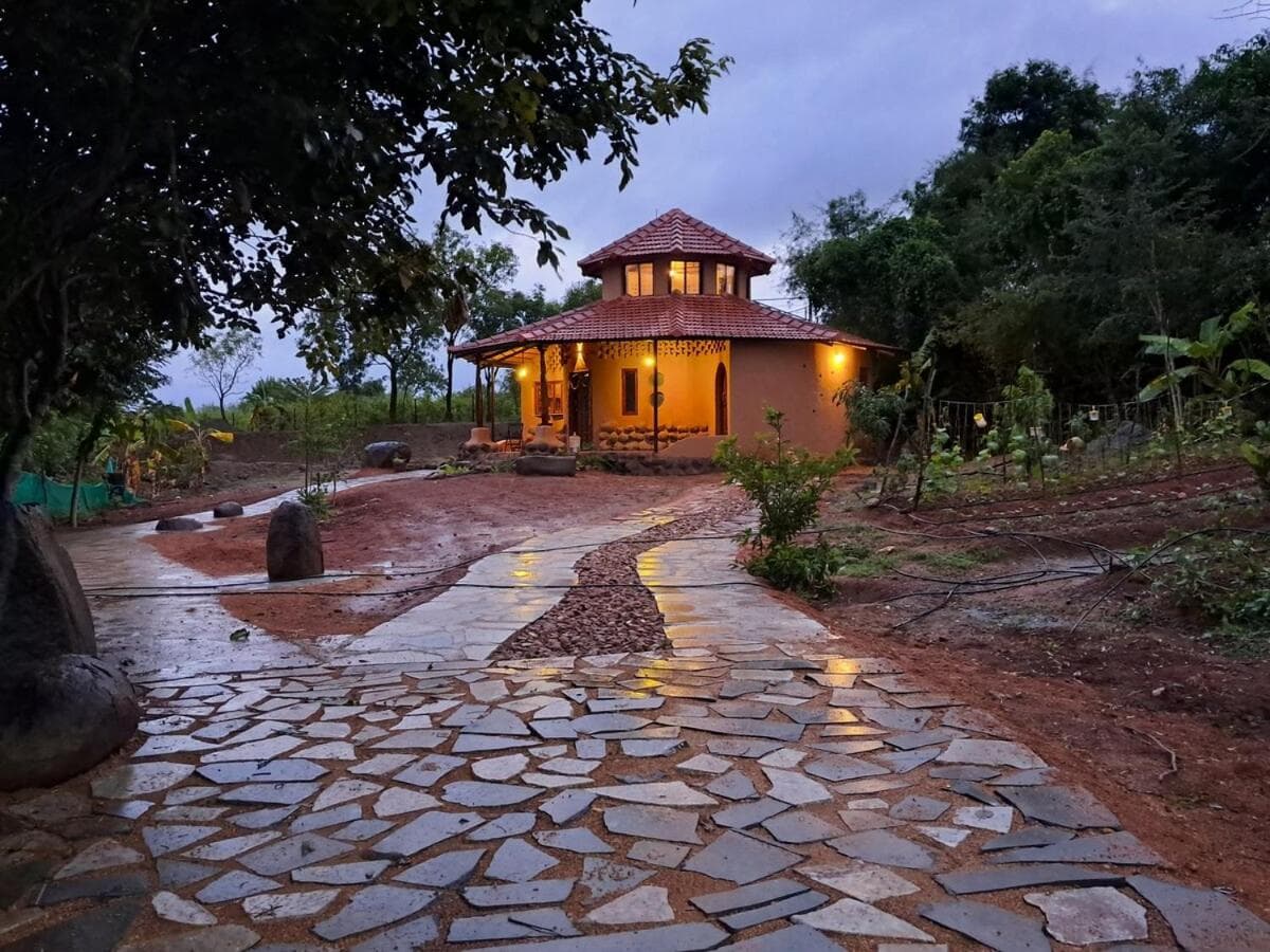 A stone path lit by lanterns leading to the round villa at dusk