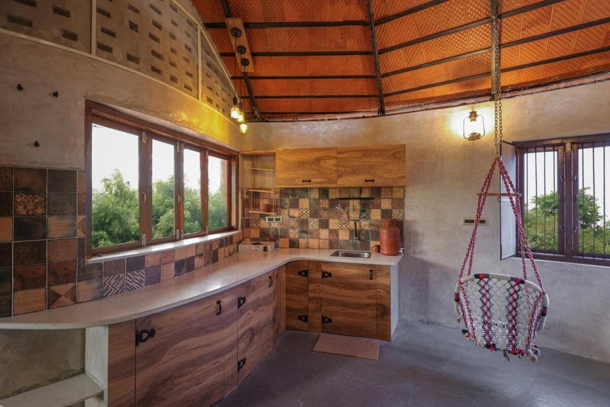 The kitchen — stone-topped wooden cabinets, a window seat and a cane swing chair