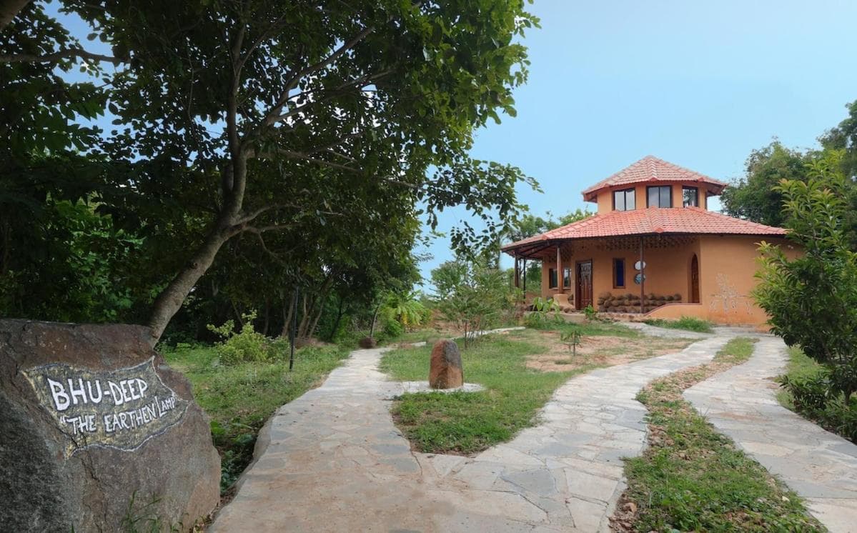 A boulder painted with the BhuDeep name beside the garden path to the villa