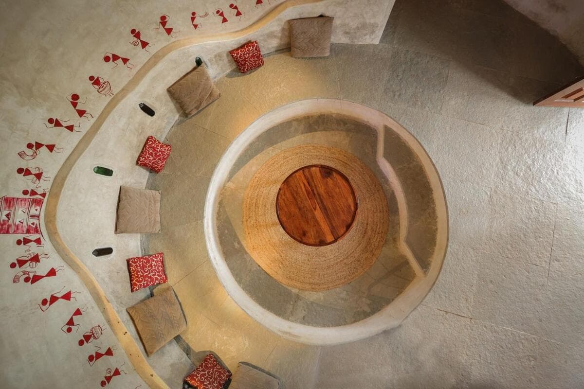 The conversation pit seen from the stair above — a circle of cushions around a wooden table
